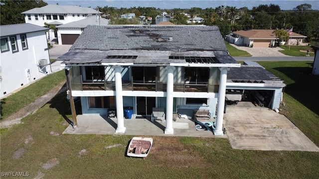 back of property with a garage, a yard, and a patio area