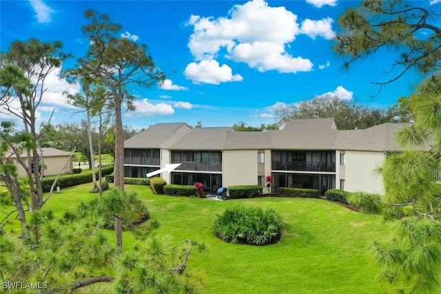 rear view of property featuring a lawn and a sunroom