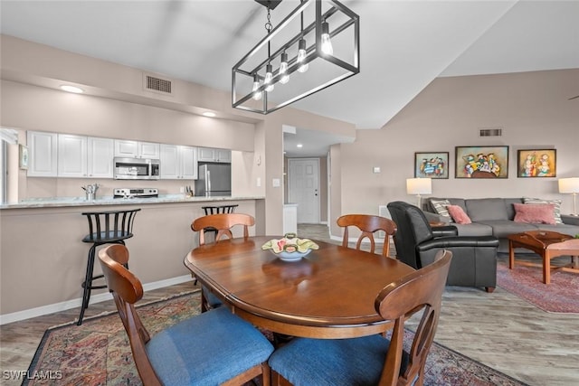 dining space featuring lofted ceiling and light wood-type flooring