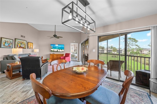 dining room with lofted ceiling, ceiling fan with notable chandelier, and light hardwood / wood-style flooring