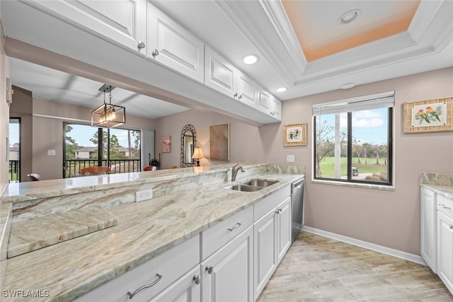 kitchen with sink, white cabinetry, decorative light fixtures, ornamental molding, and a raised ceiling