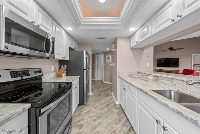 kitchen featuring crown molding, stainless steel appliances, a raised ceiling, and white cabinets