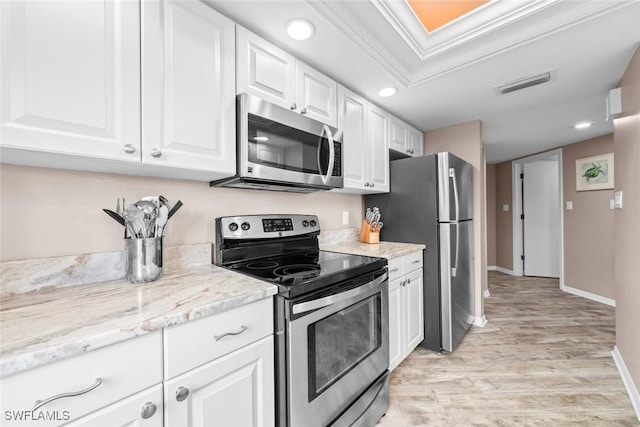 kitchen featuring stainless steel appliances, light stone countertops, ornamental molding, white cabinets, and light wood-type flooring