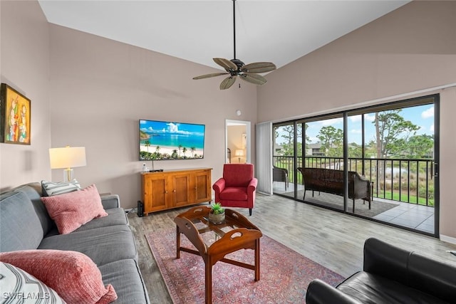 living room featuring a towering ceiling, ceiling fan, and light wood-type flooring