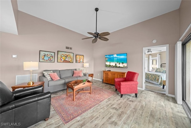 living room with ceiling fan, high vaulted ceiling, and light wood-type flooring