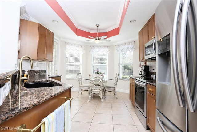 kitchen featuring light tile patterned flooring, sink, dark stone countertops, appliances with stainless steel finishes, and a raised ceiling