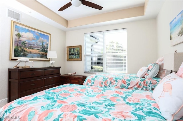 bedroom with ceiling fan and a tray ceiling