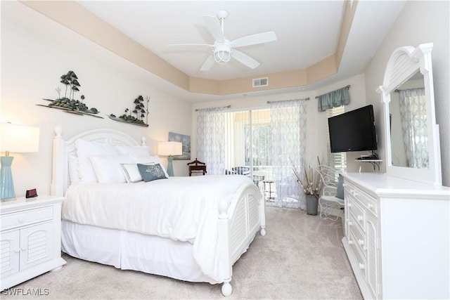 bedroom featuring a raised ceiling, access to outside, light colored carpet, and ceiling fan