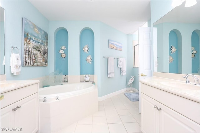 bathroom featuring tiled tub, vanity, and tile patterned flooring