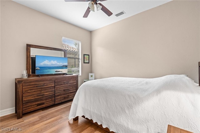 bedroom featuring visible vents, ceiling fan, baseboards, and wood finished floors