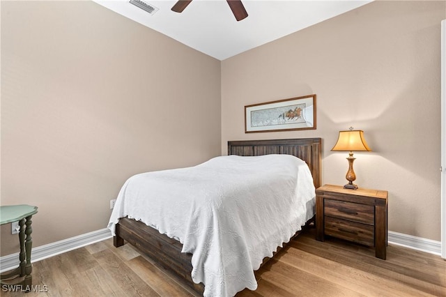 bedroom featuring baseboards, visible vents, ceiling fan, and wood finished floors