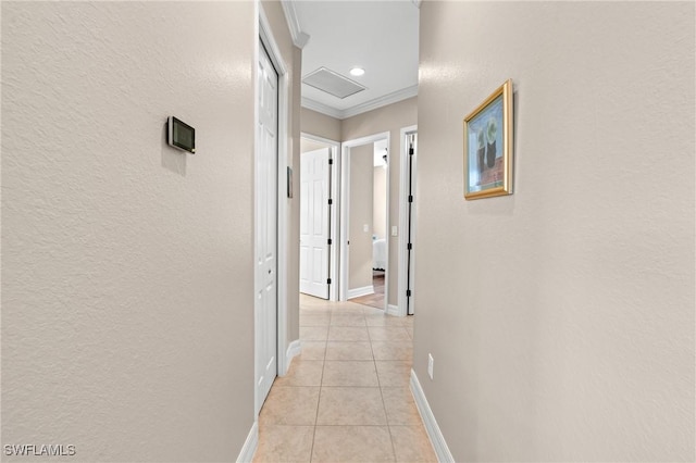 hallway featuring ornamental molding, attic access, baseboards, and light tile patterned floors