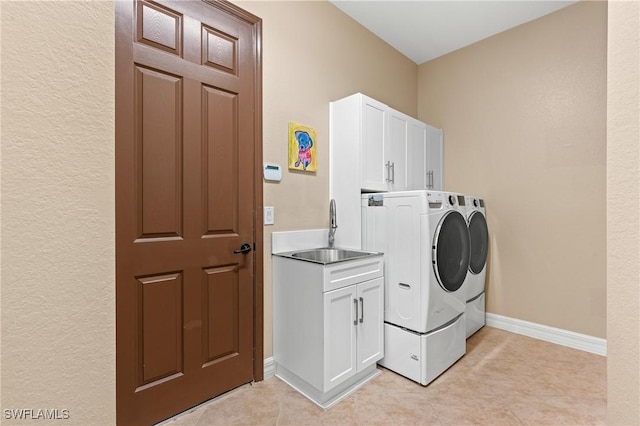 laundry area with cabinet space, baseboards, washer and dryer, a sink, and light tile patterned flooring