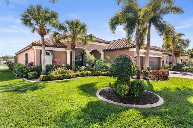 mediterranean / spanish home featuring a tile roof, stucco siding, an attached garage, a front yard, and driveway