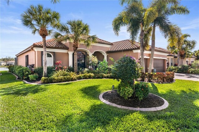 11035 Longwing Dr, Fort Myers, FL 33912 - mediterranean / spanish house with an attached garage, a tile roof, stucco siding, and a front lawn