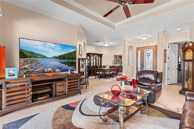 tiled living room featuring arched walkways, ornamental molding, a raised ceiling, and a ceiling fan