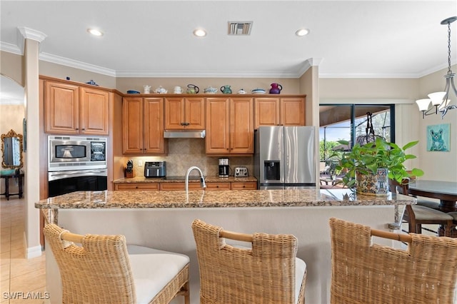 kitchen with light tile patterned floors, stainless steel appliances, backsplash, light stone countertops, and under cabinet range hood