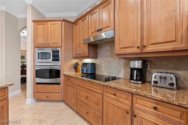 kitchen featuring arched walkways, crown molding, appliances with stainless steel finishes, light stone countertops, and under cabinet range hood