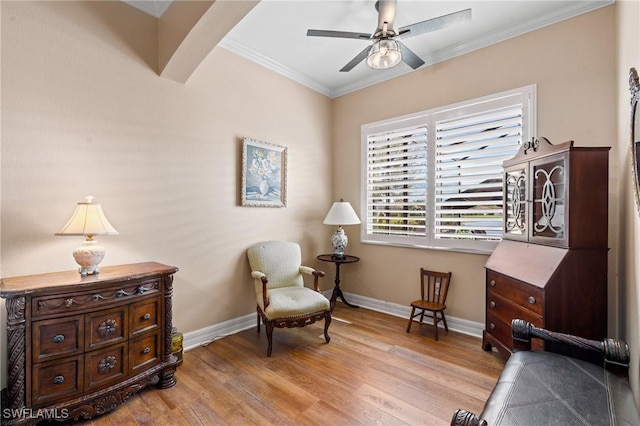 living area with ceiling fan, arched walkways, baseboards, light wood-style floors, and ornamental molding