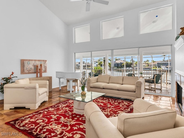 living room featuring a water view, ceiling fan, and high vaulted ceiling