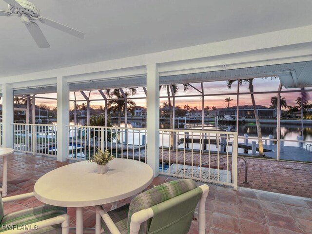 sunroom / solarium featuring a water view and ceiling fan