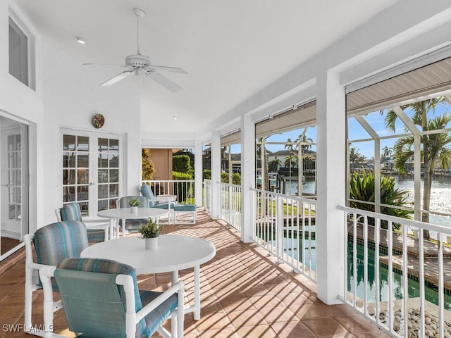 sunroom / solarium featuring a water view, plenty of natural light, and ceiling fan