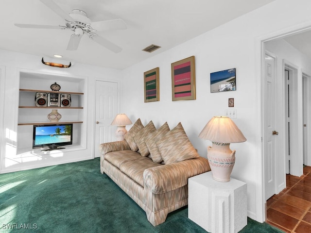 carpeted living room featuring built in shelves and ceiling fan