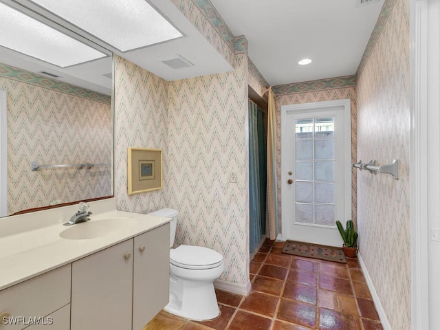 bathroom featuring tile patterned floors, vanity, toilet, and a skylight