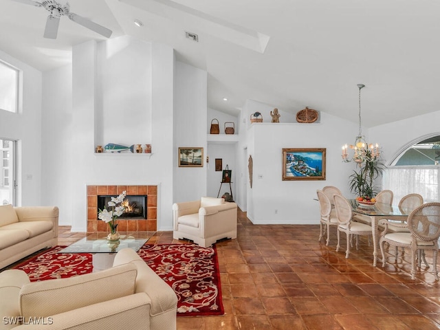 living room featuring a tiled fireplace, ceiling fan with notable chandelier, and high vaulted ceiling