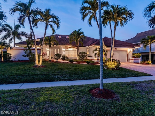 mediterranean / spanish-style home featuring a garage and a yard