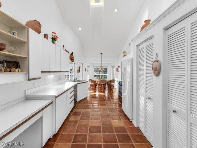 kitchen featuring pendant lighting, white cabinetry, vaulted ceiling, stainless steel dishwasher, and white fridge