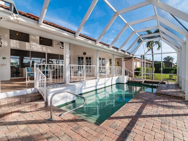 view of pool with a patio area, ceiling fan, and glass enclosure