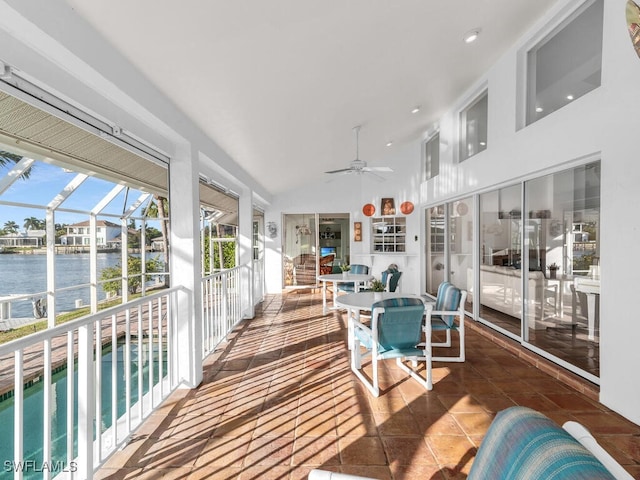 sunroom / solarium with vaulted ceiling, ceiling fan, and a water view