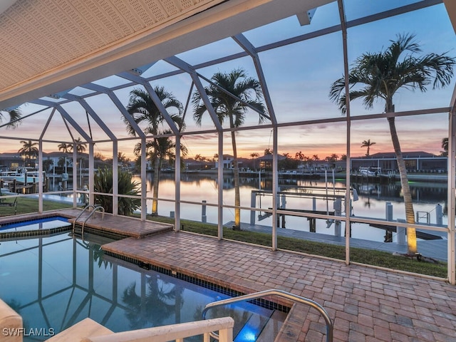 pool at dusk featuring a lanai, a boat dock, and a water view