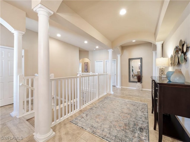 hall featuring decorative columns and light tile patterned flooring