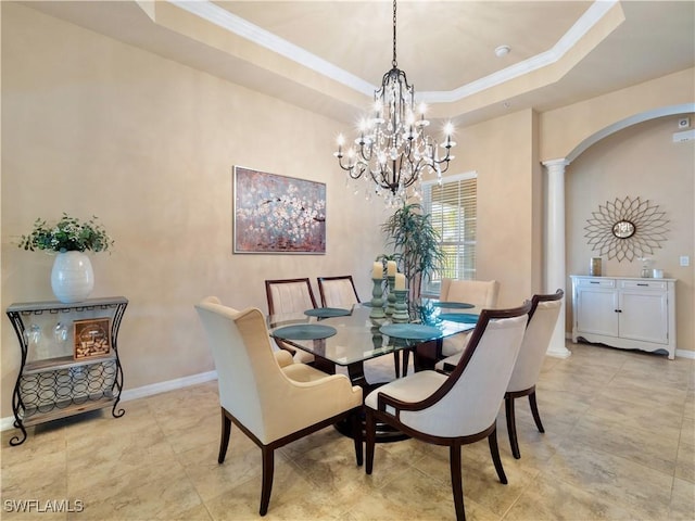 dining space featuring a raised ceiling, ornamental molding, and ornate columns