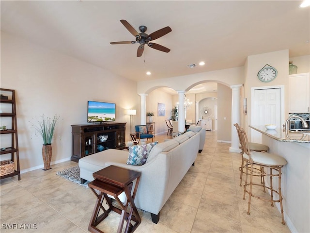 living room featuring ceiling fan, sink, and ornate columns