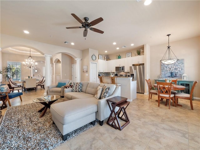 living room featuring ceiling fan with notable chandelier and decorative columns