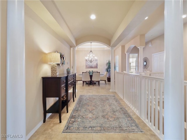 corridor with a chandelier, vaulted ceiling, and ornate columns