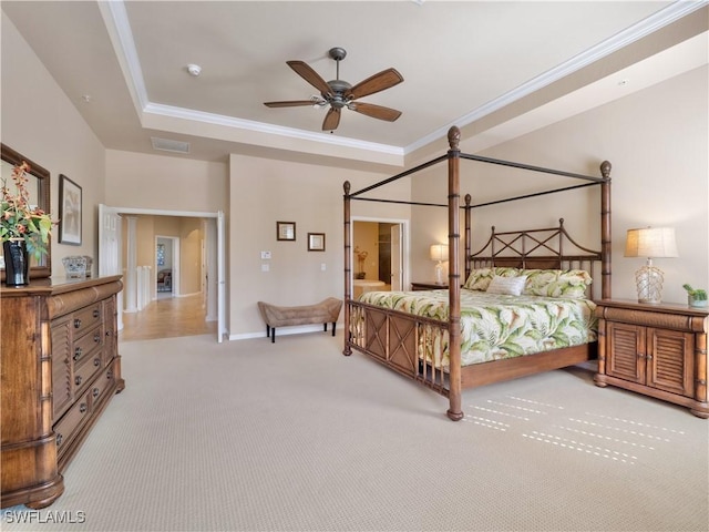 carpeted bedroom with crown molding and a tray ceiling