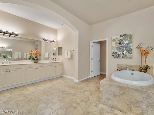 bathroom featuring tile patterned flooring, vanity, and a relaxing tiled tub