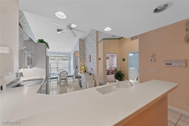 kitchen featuring light tile patterned flooring, lofted ceiling, sink, kitchen peninsula, and ceiling fan