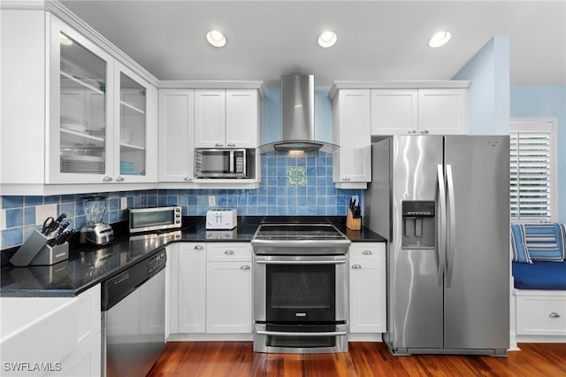 kitchen featuring wall chimney range hood, white cabinetry, stainless steel appliances, dark hardwood / wood-style floors, and decorative backsplash