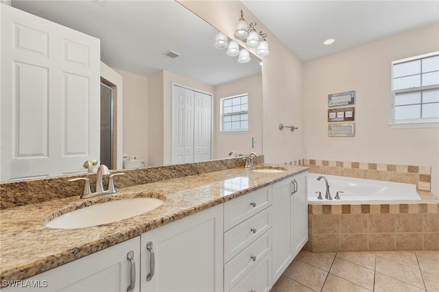 bathroom with vanity, a relaxing tiled tub, tile patterned floors, and toilet