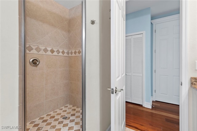 full bath with wood finished floors, a closet, and a shower stall