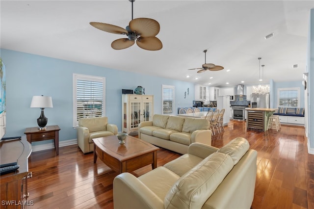 living room featuring ceiling fan with notable chandelier, plenty of natural light, and wood-type flooring