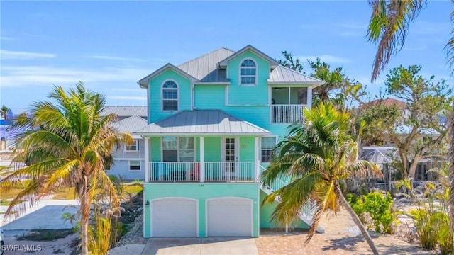 beach home featuring a garage, metal roof, a standing seam roof, and driveway