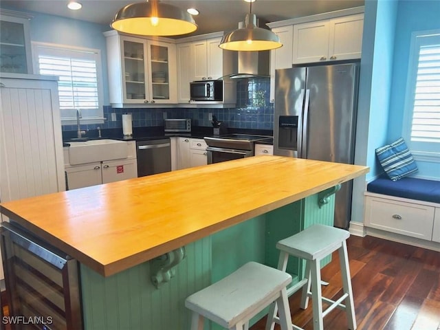 kitchen featuring appliances with stainless steel finishes, a breakfast bar, pendant lighting, and wine cooler