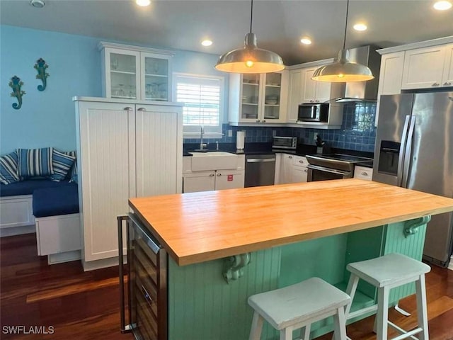 kitchen with butcher block counters, a breakfast bar area, a center island, stainless steel appliances, and white cabinets