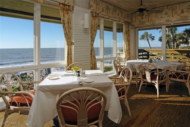 sunroom / solarium with wood finished floors and a water view